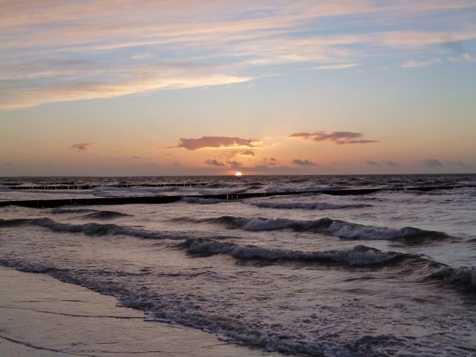 Sonnenuntergang am Meer Ein Sonnenuntergang am Meer mit leichten Wellen und einen orangefarbenden Himmel.